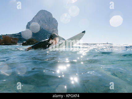 L'homme nage avec sa planche de surf en essayant d'attraper une vague dans la mer méditerranée. Banque D'Images