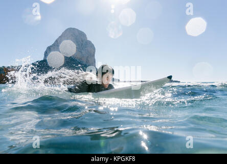 L'homme nage avec sa planche de surf en essayant d'attraper une vague dans la mer méditerranée. Banque D'Images