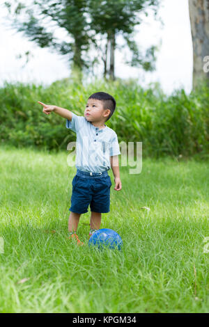 Petit enfant jouer au foot ball et finger point de côté Banque D'Images