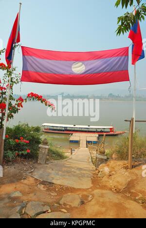 Drapeau Laos séparant la frontière entre la Thaïlande, le Vietnam et le Myanmar au Golden Triangle, des cheminements qui mènent à une jetée. Banque D'Images