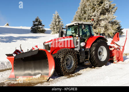 Grand tracteur rouge avec chasse-neige au cours d'un hiver Banque D'Images