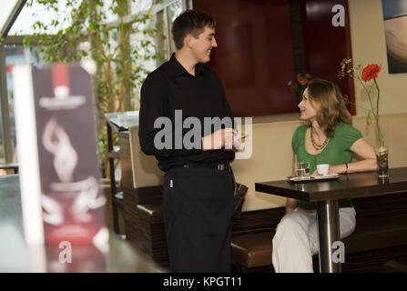 Parution du modèle , Kellner bedient junge Frau im Kaffeehaus - in cafe Banque D'Images