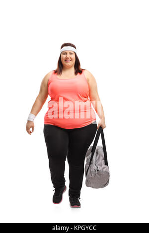 Portrait d'une femme en surpoids avec un sac de sport à marcher en direction de l'appareil isolé sur fond blanc Banque D'Images