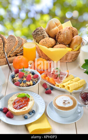 Petit-déjeuner servi à l'extérieur en été avec une tasse de Cappuccino et un grand choix de nourriture Banque D'Images