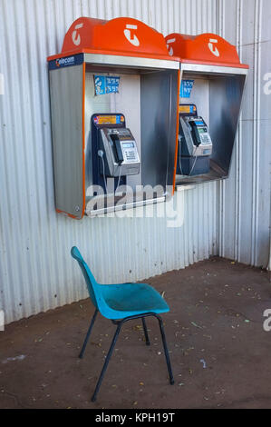 Une chaise bleue en face de deux téléphone public de la société Telstra dans l'outback australien. Telstra est l'opérateur de téléphonie nationale australienne. Banque D'Images