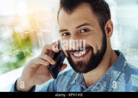 L'homme joyeux élégant avoir conversation téléphonique et souriant. Banque D'Images