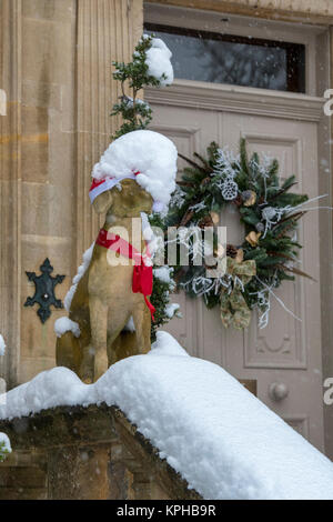 Statue de chien Noël Décoration guirlande de porte et dans la neige à l'extérieur d'une maison de ville à Chipping Campden, Cotswolds, Gloucestershire, Angleterre Banque D'Images