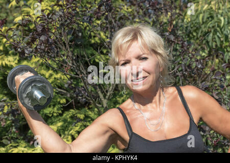 Le senior woman holding est un haltère en plein air Banque D'Images