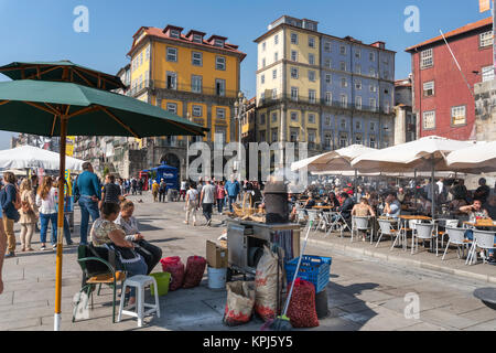 La vente de châtaignes grillées sur le Cais da Ribeira, sur le front de mer, dans le quartier de Ribeira de Porto, Portugal Banque D'Images