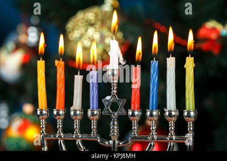 La menorah avec des bougies pour la fête des lumières en arrière-plan de l'arbre du Nouvel An. L'éclairage de Studio Banque D'Images