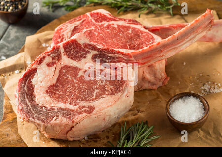 Nourri à l'herbe rouge cru Steaks Tomahawk au romarin Banque D'Images