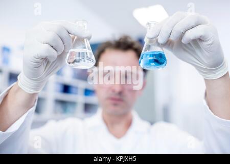 Assistant de laboratoire mâles tenant deux flacons de produits chimiques. Banque D'Images