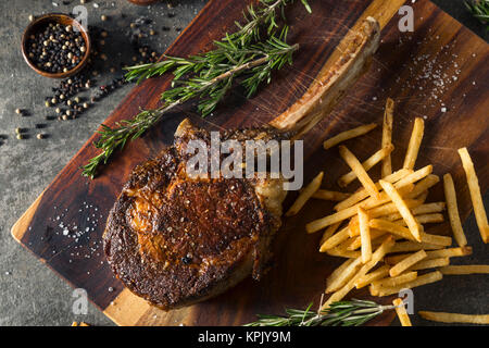 Les steaks cuits Tomahawk nourri à l'herbe avec des frites et de romarin Banque D'Images