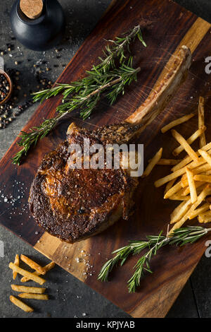 Les steaks cuits Tomahawk nourri à l'herbe avec des frites et de romarin Banque D'Images