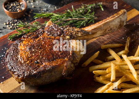 Les steaks cuits Tomahawk nourri à l'herbe avec des frites et de romarin Banque D'Images