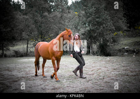 Une adolescente se promène avec son cheval dans un champ pendant la formation ; British Columbia, Canada Banque D'Images