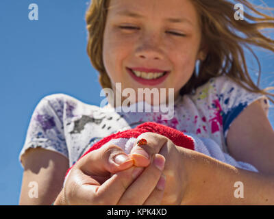 Une jeune fille montre une coccinelle (Coccinellidae) et elle s'est tenue sur son pouce ; Destin, Floride, États-Unis d'Amérique Banque D'Images