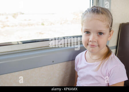 Happy girl assis sur une chaise par la fenêtre dans un train électrique de banlieue Banque D'Images