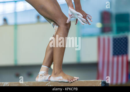 Fille gymnaste sur l'appareil non identifié de faisceau libre résumé jambes mains chevilles attachés bandes bandages qui continuent à jouer la concurrence de routine. Banque D'Images