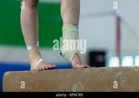 Fille gymnaste sur l'appareil non identifié de faisceau libre résumé chevilles pied jambe blessures orteil bande pansements attaché qui continuent à jouer la concurrence routi Banque D'Images