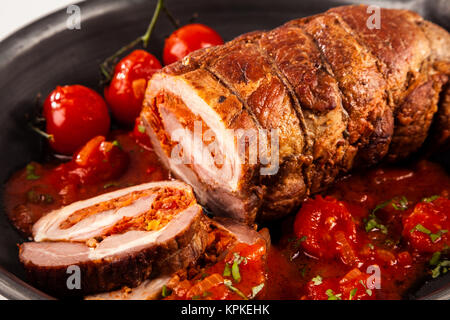 Close up de rôti de porc farci aux tomates cerises assis dans poêle en fonte Banque D'Images