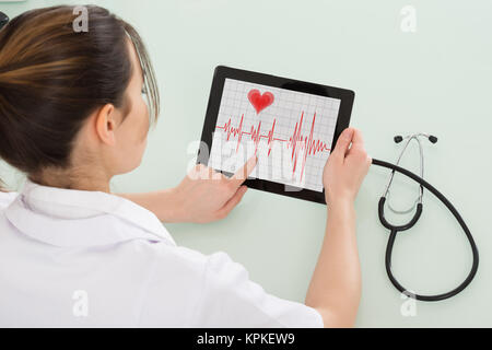 Cardiologue femelle analyse pulsation sur tablette numérique Banque D'Images