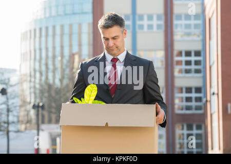 Businessman Standing avec boîte en carton à l'extérieur du bureau Banque D'Images