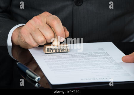 Close-up of Businessman Hand piétinement sur le formulaire de contrat approuvé Banque D'Images