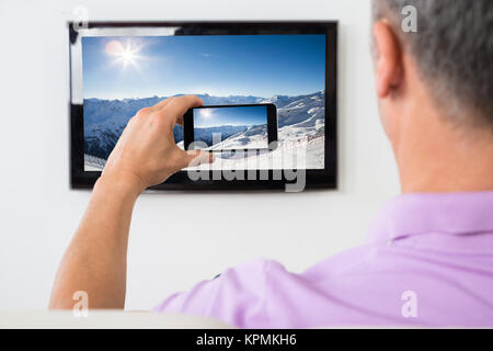 L'homme avec le smartphone connecté à un téléviseur Regarder la vidéo Banque D'Images