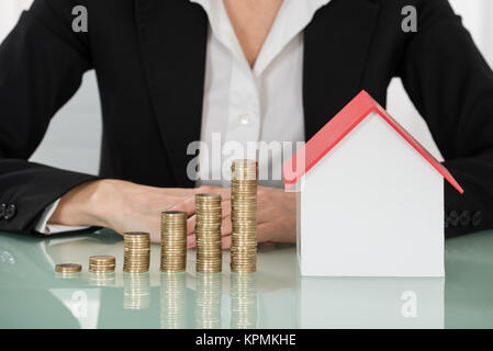 Businesswoman With House Model et empilés pièces sur 24 Banque D'Images