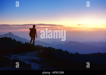 La silhouette de l'homme sur la toile de montagnes au coucher du soleil Banque D'Images