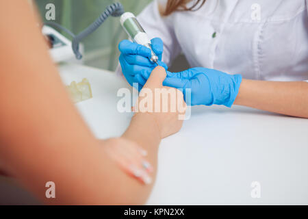 Libre shot d'une femme à l'aide d'un poussoir de cuticle de donner un ongle manucure. Nail technician client donnant une manucure au salon de manucure. Young caucasian woman receiving a French manucure. Banque D'Images