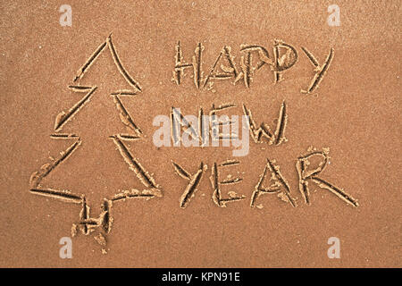 L'inscription sur le sable bonne année et l'arbre de Noël. Banque D'Images