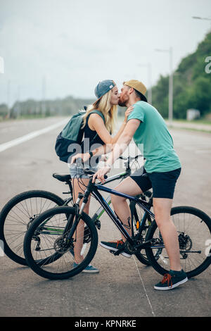 Beau jeune couple dans l'amour de marcher avec des bicyclettes, embrasser et s'étreindre Banque D'Images