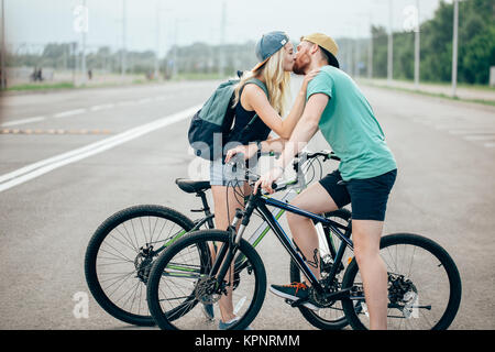 Beau jeune couple dans l'amour de marcher avec des bicyclettes, embrasser et s'étreindre Banque D'Images