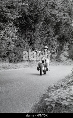 Biker avec outstretced d'armes sur un chemin de campagne dans le Berkshire. Des scènes de la Harley Davidson Road rally dans les motifs de Littlecote House, Berkshire, Angleterre le 30 septembre 1989 l'ion. La manifestation était organisée par Peter de Savary qui possédait la chambre à ce moment-là. Banque D'Images