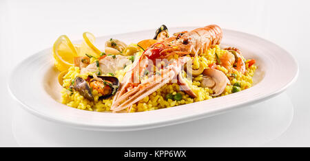 Close Up Still Life View de la Paella espagnole traditionnelle plat composé de riz jaune safran et des fruits de mer et crustacés servis en plateau blanc moderne sur fond blanc Banque D'Images