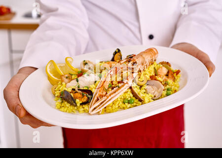 Seul blanc de forme ovale plat de pâtes et le homard servi par un tablier rouge en cuire non identifiables Banque D'Images