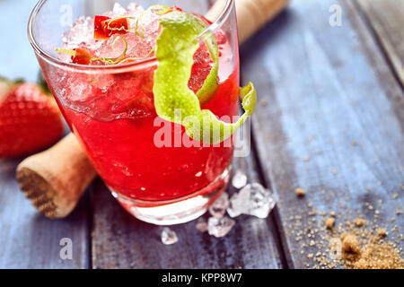 Glace fraise piquante rouge slush verre dans le verre avec de la chaux et de Peel en bois à côté de la fraise, les épices et d'un concasseur de glace sur le tableau Banque D'Images