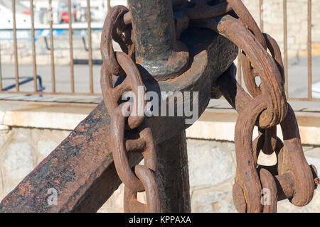 Old anchor est allongé sur les rochers près du port sur l'île de Crète. Banque D'Images