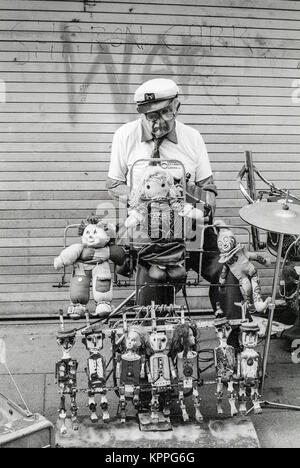 One Man Band, vieil homme à visage triste à l'accordéon et de l'exploitation d'une étrange mis en place avec poupée danseuse, Dublin, Irlande. 1989 Banque D'Images