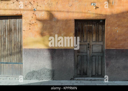 Ombre d'un chien-un mur extérieur de jaune, orange et gris, une porte en bois, et une ombre qui ressemble à un chien, à San Miguel de Allende Banque D'Images