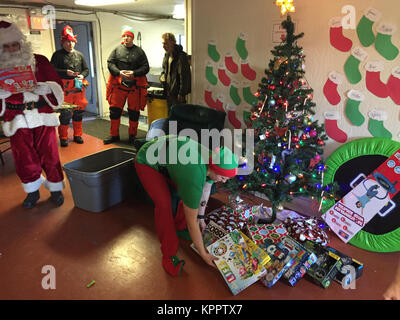 Le Père Noël et sa tête elf offrir des cadeaux de Noël pour les enfants de l'école Danger Bay sur l'île Kodiak, Alaska, 5 décembre 2017. La station de la Garde côtière canadienne les équipages d'hélicoptères Kodiak aident le Père Noël Offrir des jouets à l'éloignement de l'île Kodiak villages au cours des 43 dernières années. La Garde côtière américaine Banque D'Images
