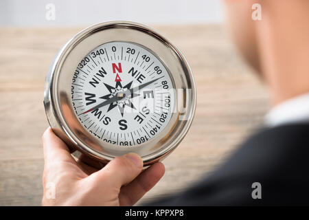 Close-up of Businessman Holding Compass In Office Banque D'Images