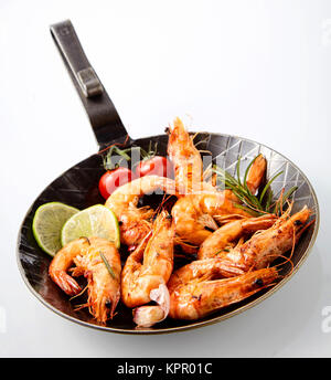 Délicieux grillés marinés crevettes épicées queen parfumé au romarin et servi avec des tranches de citron frais et les tomates dans une poêle white Banque D'Images