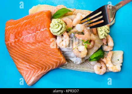 Diverses espèces de poissons crus en filets comme le saumon, le cabillaud et les crevettes. Banque D'Images