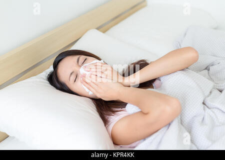 Femme éternue on bed Banque D'Images