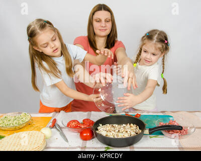 Mère de deux filles à la table de la cuisine avec un plat de champignons est versée dans le bac Banque D'Images