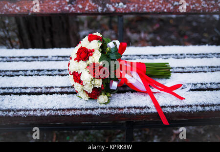 Bouquet de mariage sur un banc de parc d'hiver Banque D'Images