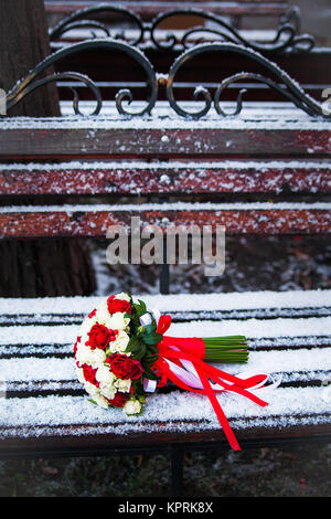 Bouquet de mariage sur un banc de parc d'hiver Banque D'Images